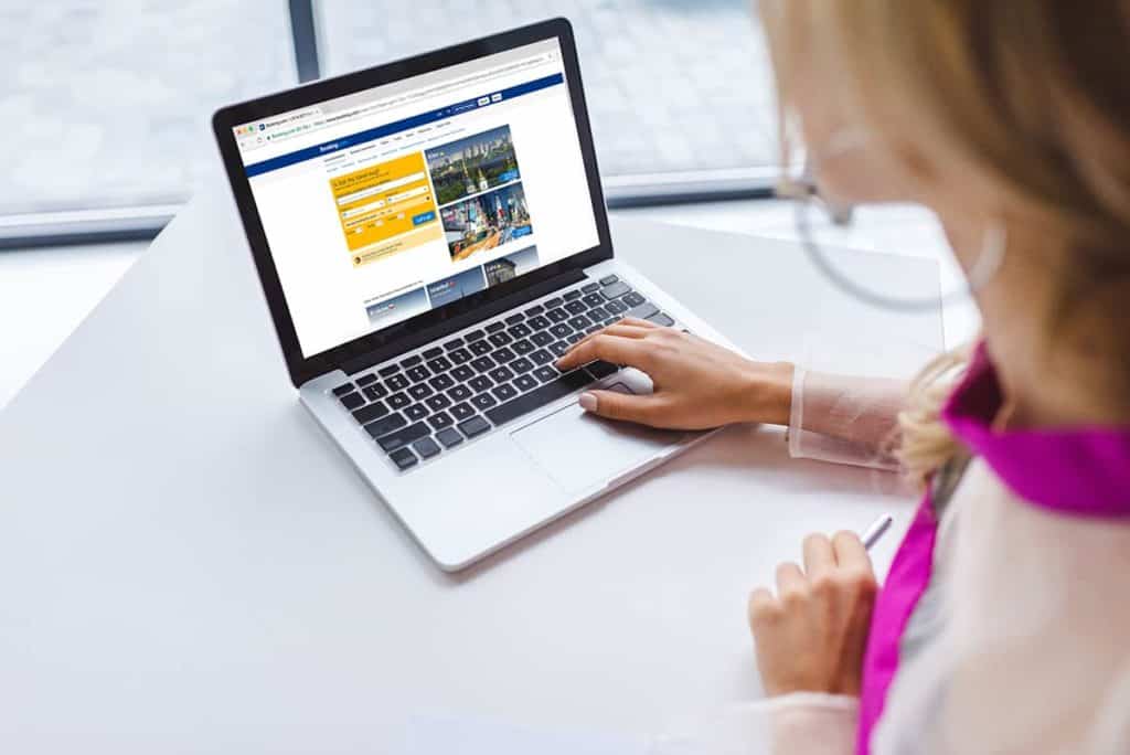 cropped-view-of-woman-using-laptop-with-booking-we-4QJ2DJC
