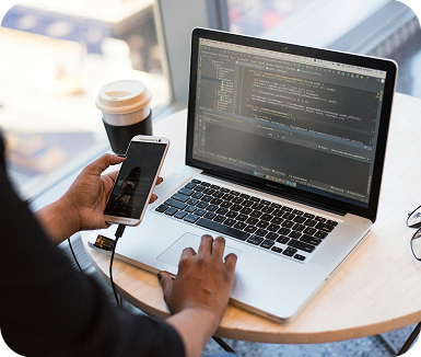 A person working on laptop and scrolling phone