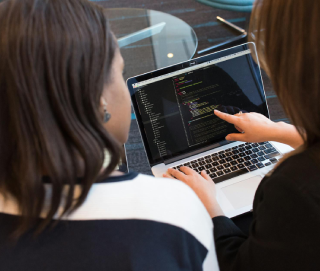 Two girls watching laptop and discussing