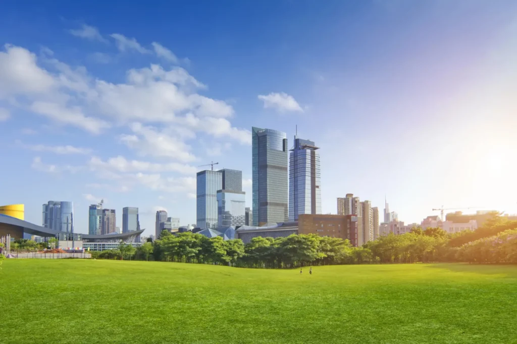 Green park with visitors, trees, and a modern city skyline of glass