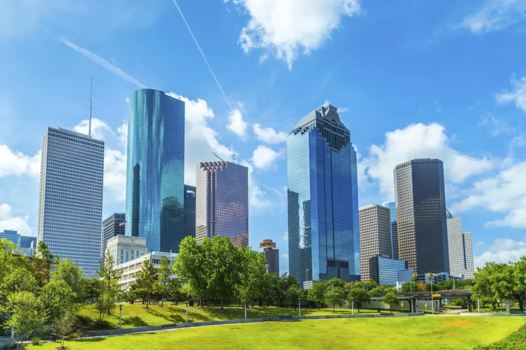 Sunny Houston skyline with tall glass and concrete skyscrapers behind a green park