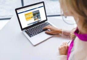 Cropped view of woman using laptop with booking website